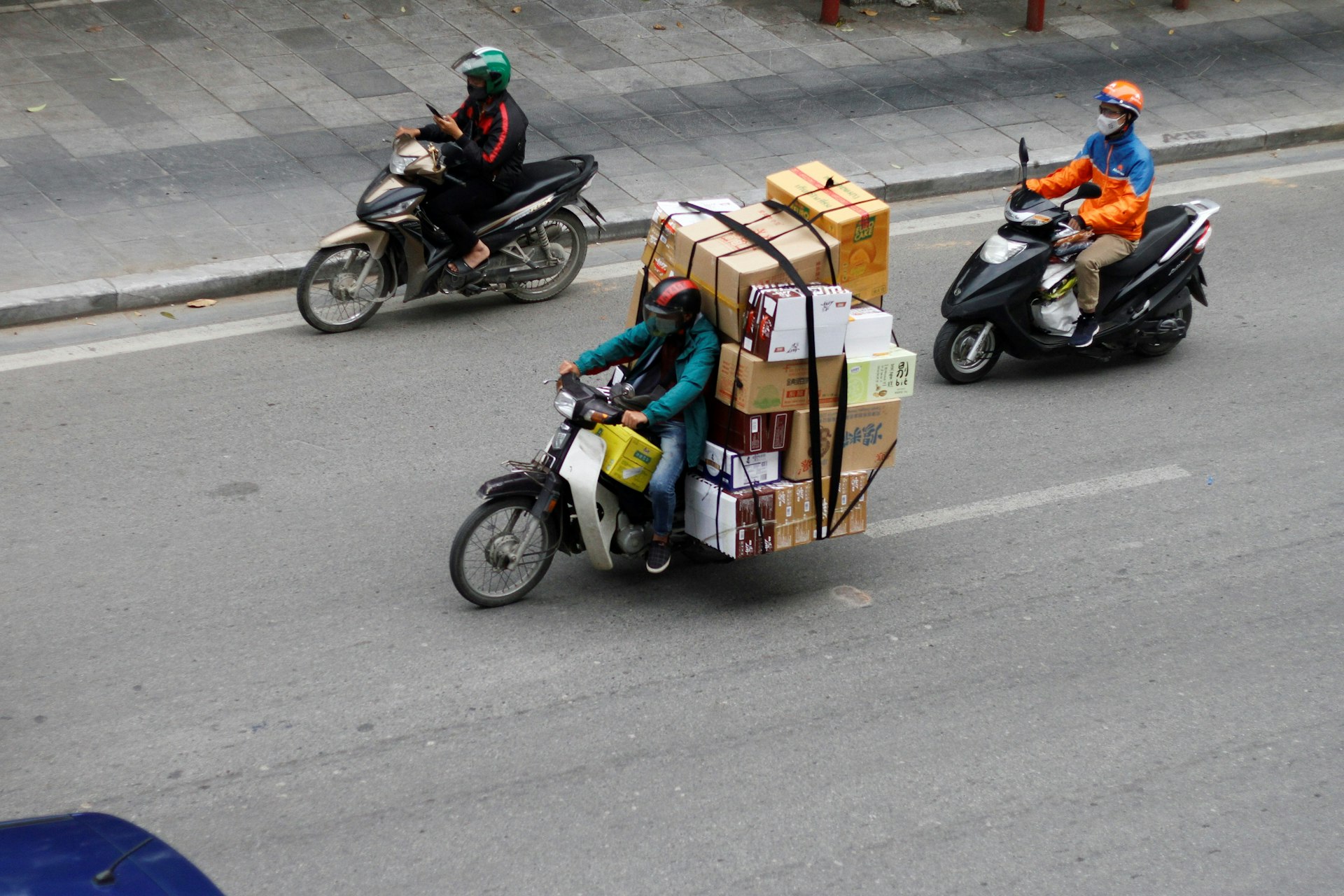 Motorcyclists carrying large loads on a street